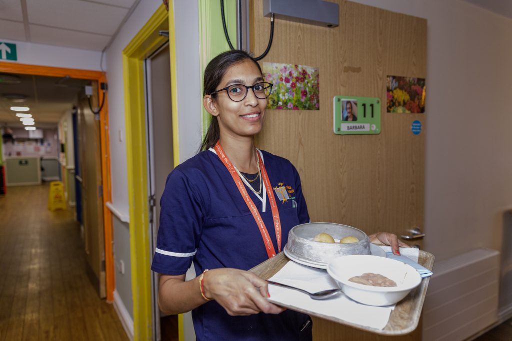 Health care worker in corridor with tray